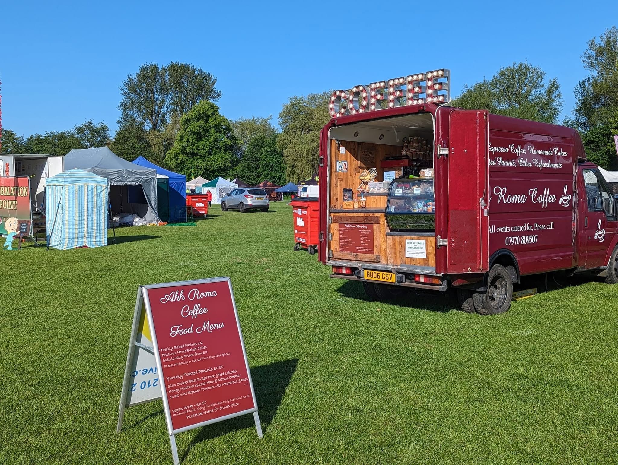 The Ahh Roma red coffee van serving at an outdoor event on a sunny day